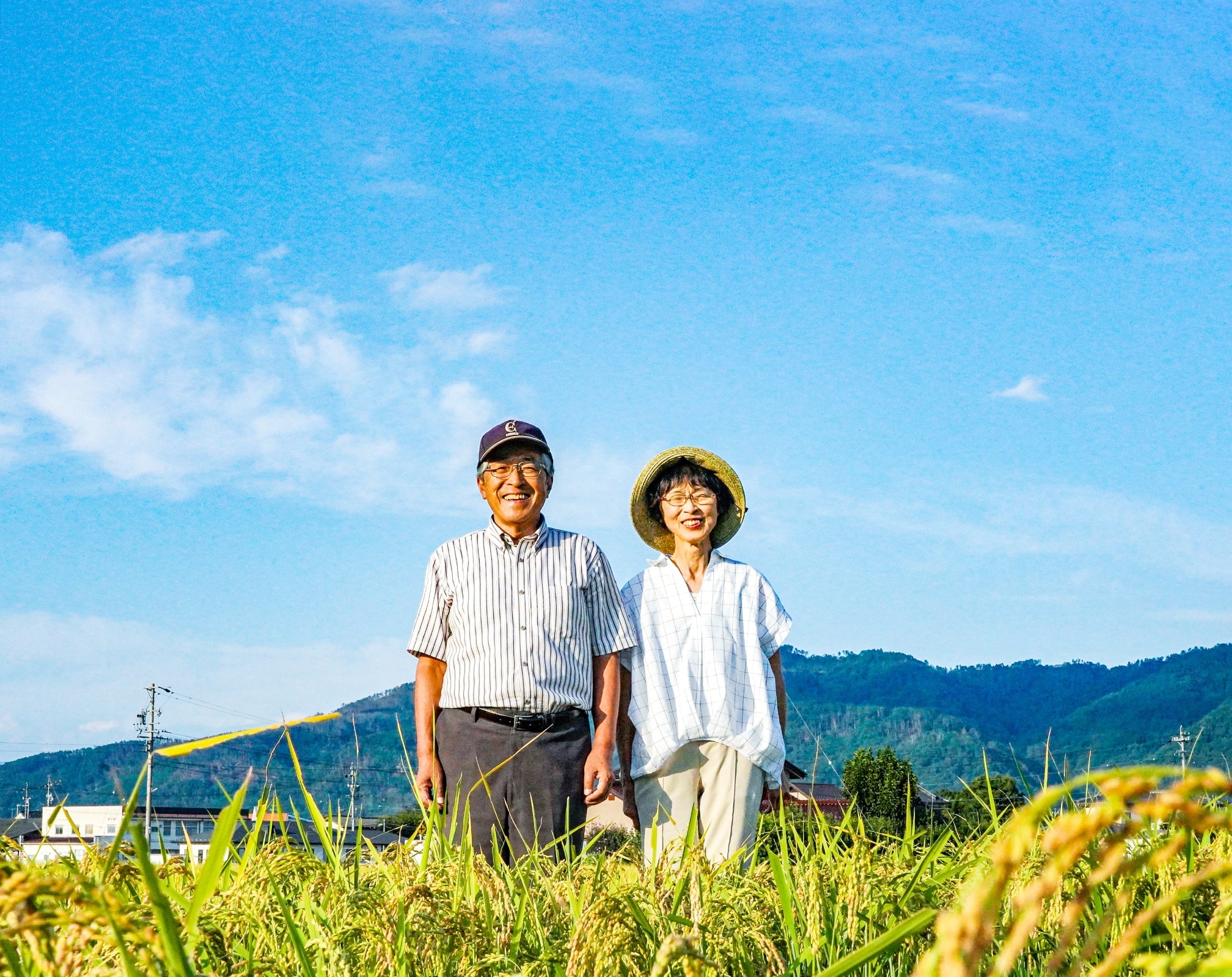 夫婦が笑顔で田んぼに立っている写真